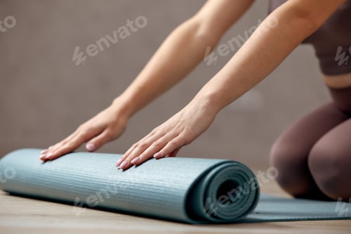 Preview: Woman Rolling Out Yoga Mat on Floor
