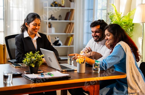 Preview: Indian married young couple showing excitement and happiness looking at laptop in an office
