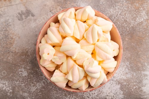 Preview: Orange and pink marshmallow in ceramic bowl on brown concrete background, top view, copy space