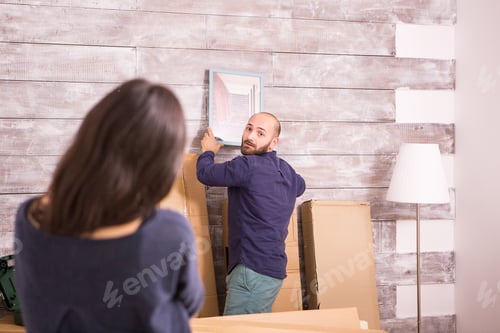 Preview: Girlfriend helping her boyfriend to hang picture on the wall