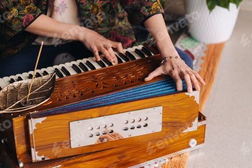 Preview: Hands of a woman sitting on the floor and playing the harmonium during the practice of kundalini