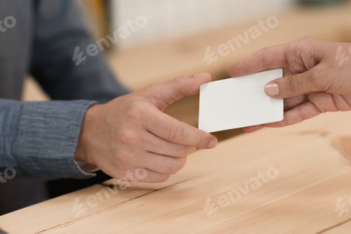 Preview: partial view of woman giving credit card to waiter for payment in cafe