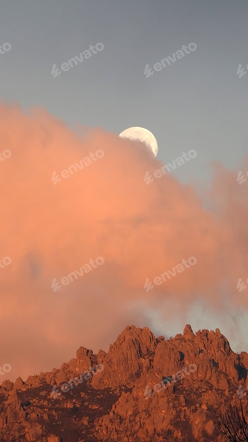 Preview: Vertical shot of the orange clouds covering moon and rocks