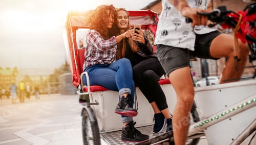 Preview: Teenage girls sitting on tricycle using mobile phone