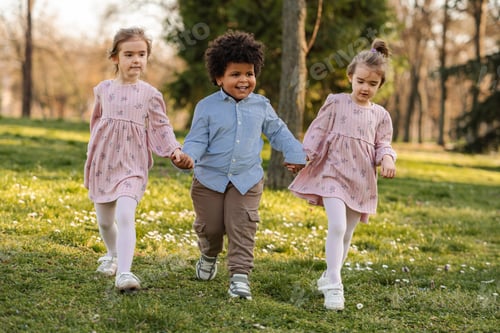Preview: Diverse children holding hands walking in spring park