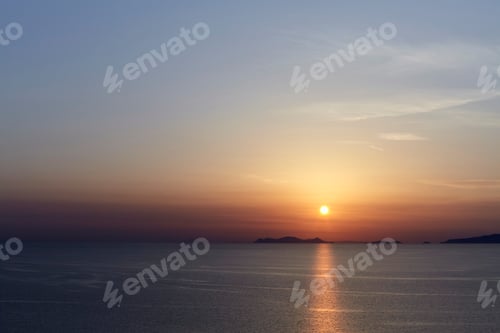 Preview: Sunset over a calm sea with islands silhouetted against the sky.
