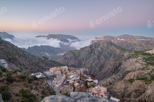 Preview: Scenic view of a mountain village in Al Hajar Mountains, Oman, with misty clouds and a colorful sky