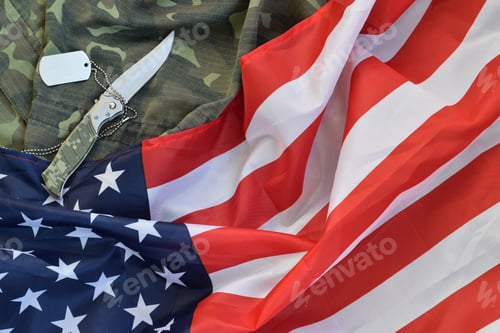 Preview: Army dog tag token and knife lies on Old Camouflage uniform and folded United States Flag