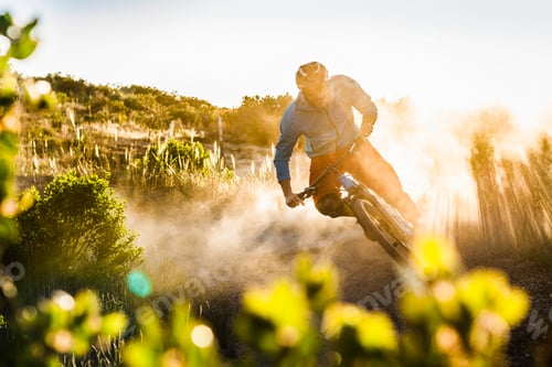 Preview: Mountain biker races down a dusty trail at sunset