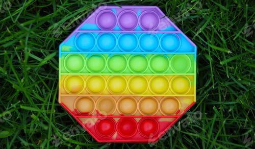 Preview: Pop it silicone anti-stress toy. The child plays on the grass. New trend Selective focus.