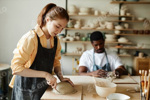 Preview: Woman shaping handmade ceramic bowl in cozy pottery studio