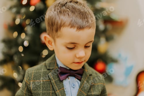 Preview: Cute little boy in festive costume with butterfly on Christmas tree background