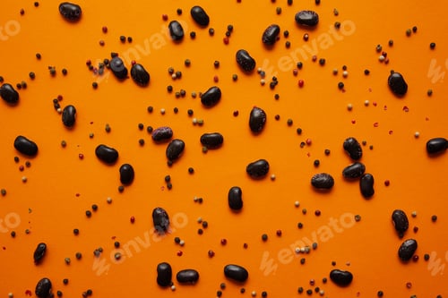Preview: top view of haricot beans and peppercorns on orange background