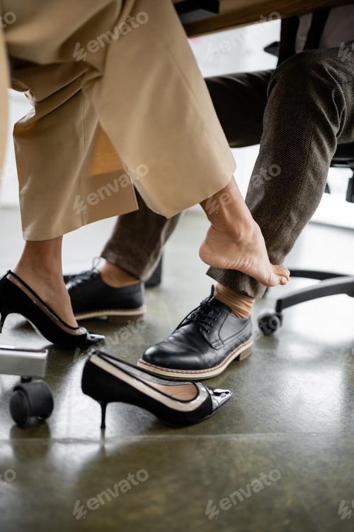 Preview: partial view of young african american woman seducing businessman under office desk