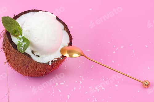 Preview: Vanilla ice cream balls in a fresh coconut half decorated with mint leaves with a spoon on a pink