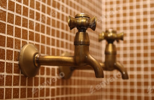Preview: Vintage brass water faucets against a warm, tiled background