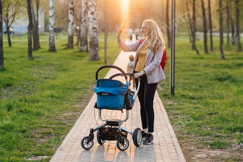Vorschau: Mama geht mit Kinderwagen mit Smartphone-Videoanruf im Park