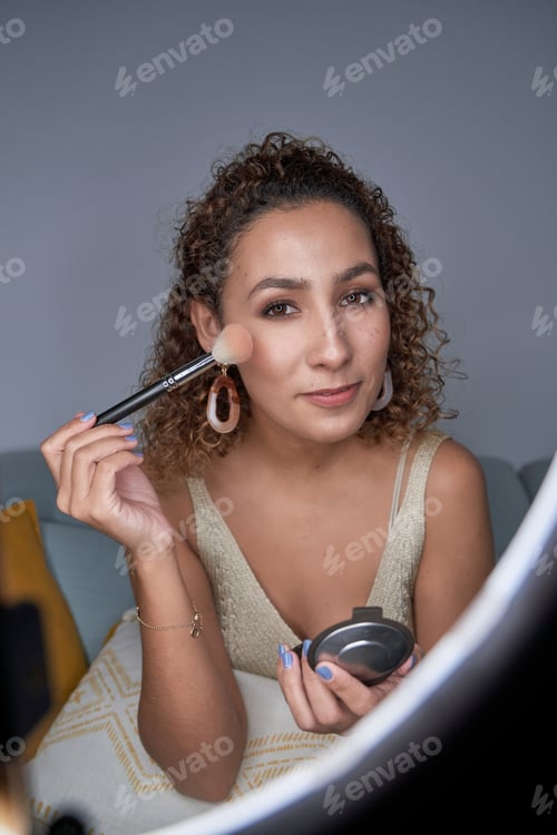 Preview: Young positive female blogger demonstrating applying of highligh