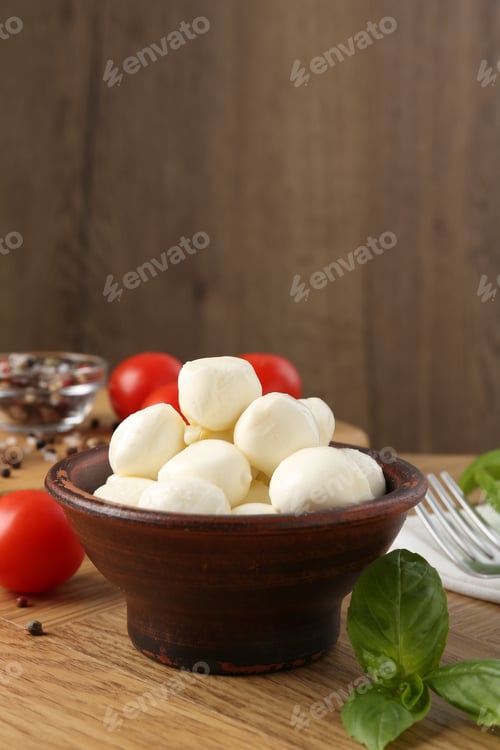 Preview: Tasty mozzarella balls, tomatoes, peppercorns and basil on wooden table, closeup