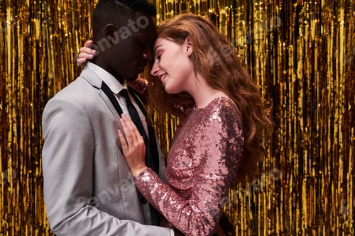 Preview: Side view of young romantic multiracial couple in stylish apparel embracing while celebrating New