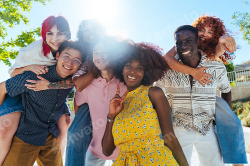 Preview: Multiethnic group of young friends meeting and having fun outdoors