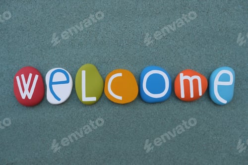 Preview: Welcome, creative word composed with multi colored stone letters over green sand