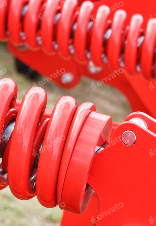Preview: Hard red spring made of steel. Part of big industrial or agricultural machine