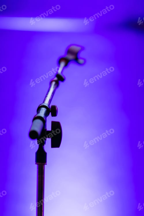 Preview: Selective focus shot of a microphone stand on a bright blue background