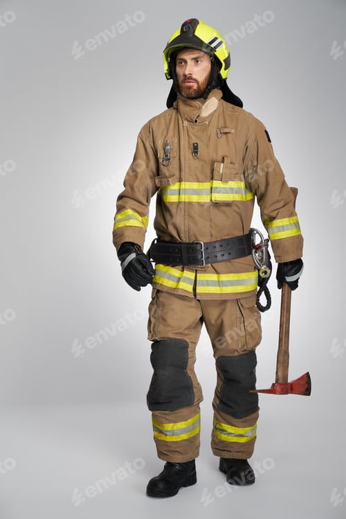 Preview: Bearded male fireman carrying sharp axe, while walking.