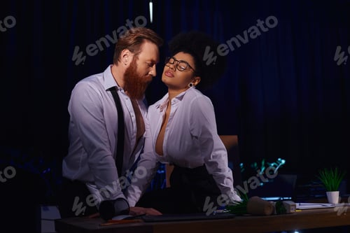 Preview: passionate african american woman in eyeglasses seducing bearded businessman in office at night