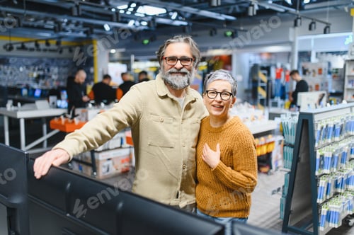 Preview: Mature couple smiling buying new electronics in store