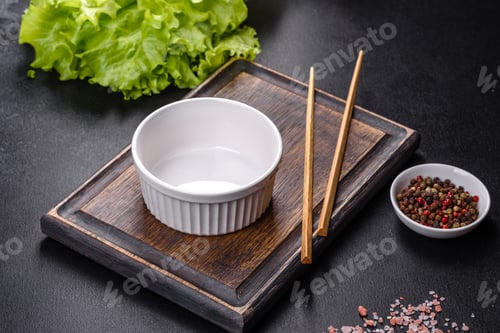 Preview: An empty white bowl and sticks on a wooden cutting board