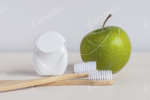 Preview: Bamboo toothbrushes, green apple and dental floss on white background