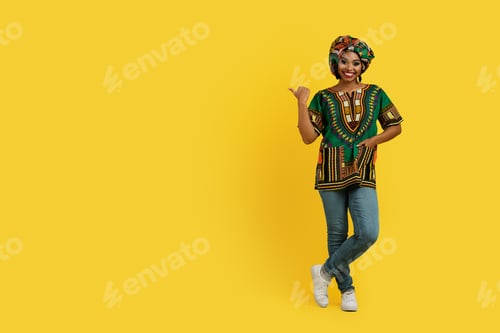 Preview: Attractive african lady in colorful outwear pointing at copy space