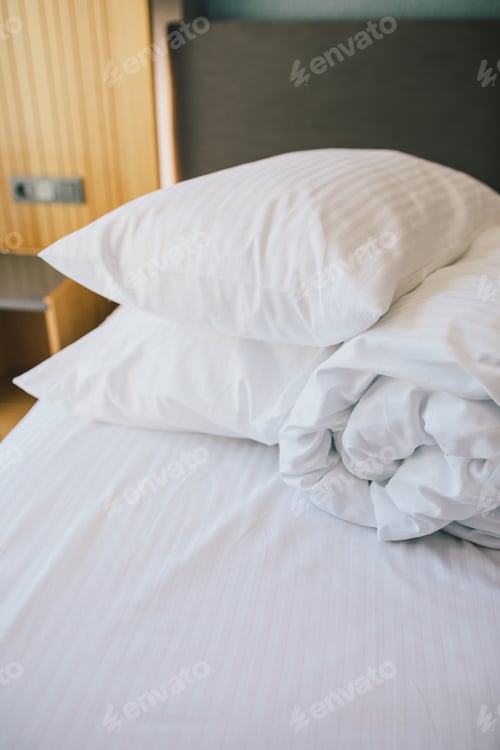 Preview: Bed and white linens in a hotel room.