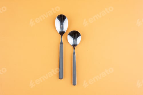 Preview: Above view of stainless teaspoons lying side by side on golden background with free space
