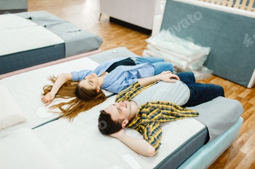 Preview: Love couple lying in bed, furniture store showroom