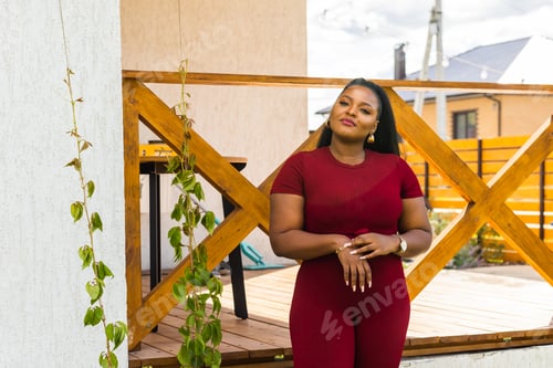 Preview: Beautiful african american woman enjoying evening on village and nature on terrace of country house