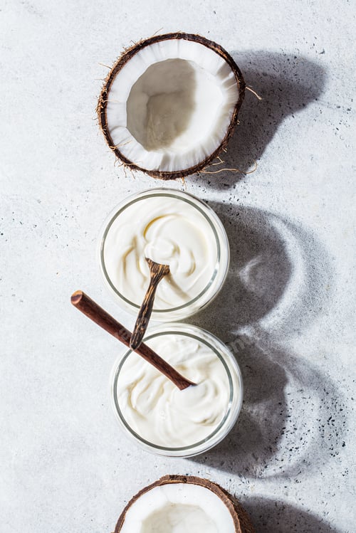 Preview: Flat lay of coconut yogurt in glass jars, white background, top view. Vegan food concept.