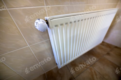 Preview: Close-up of white heating radiator with thermostat valve ion tiled walls