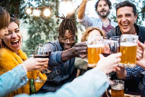 Happy friends celebrating with beer and wine toasting in evening gathering