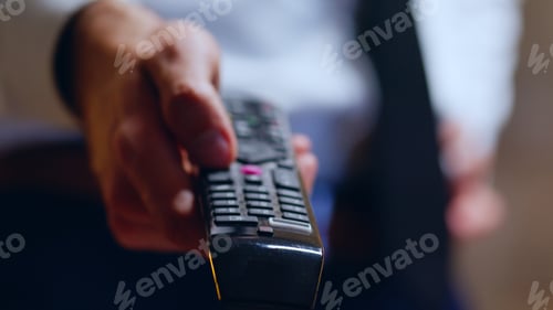 Preview: Close up of businessman relaxing after work using tv remote control