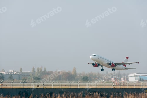 Preview: Jet plane above airport runway with cloudy sky at background