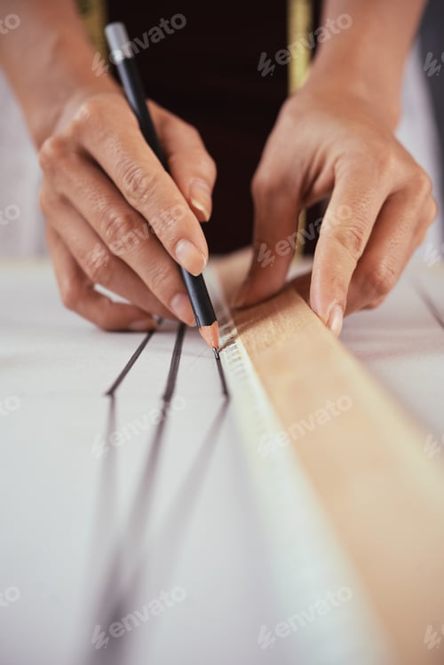 Preview: Unrecognizable tailor drafting lines on pattern