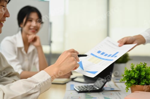 Preview: Male employee analyzing sales statistics document with team during corporate meeting.