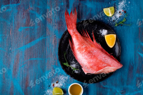 Preview: Beaked redfish or perch prepared for cooking a meal with other ingredients around on the blue table.
