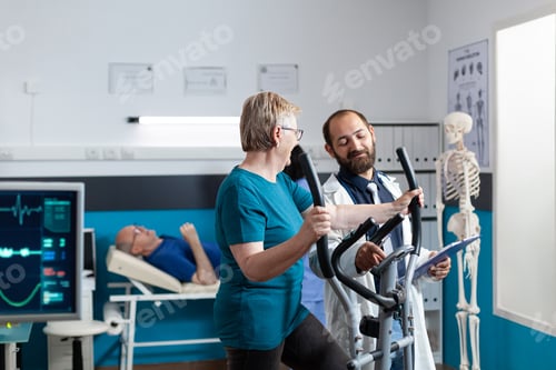 Preview: Doctor talking to old patient doing physical exercise to recover