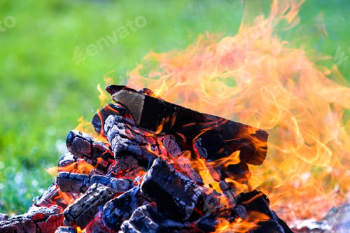 Preview: Glowing bonfire on nature. Burning wooden planks outside on summer day.