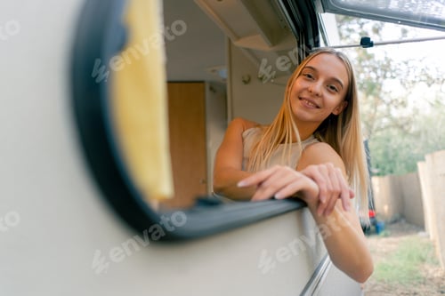 Preview: A young girl looks out of an open window while riding in a trailer on trip and smiles joyfully