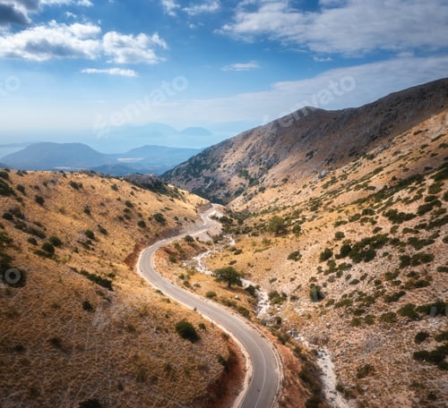Preview: Aerial view of winding mountain road, blue sky at sunrise